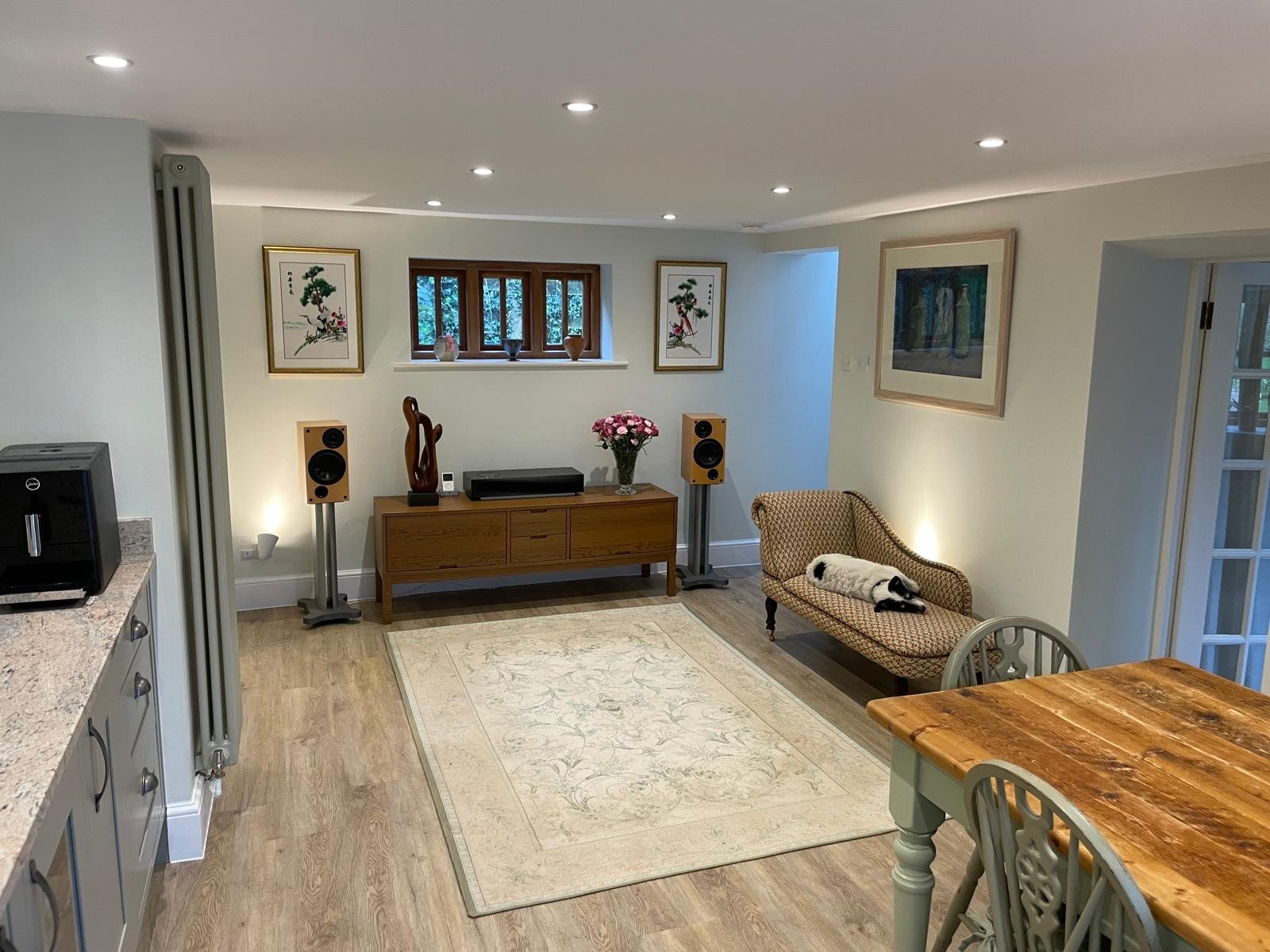 Open-concept kitchen and living room with granite counters, wooden furniture, and modern lighting fixtures throughout the space.
